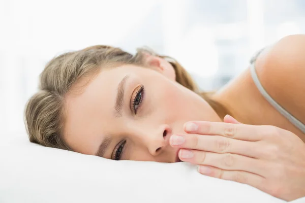Friedliche müde Frau liegt gähnend in ihrem Bett — Stockfoto