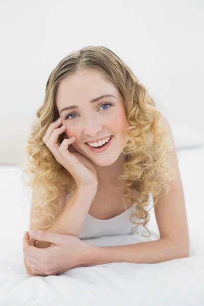 Dość uśmiechający się blondynka, leżąc na łóżku patrząc na kamery — Zdjęcie stockowe