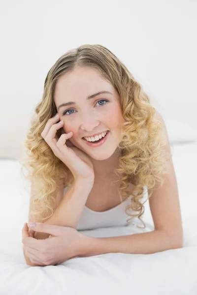 Vrij lachende blonde liggend op bed camera kijken — Stockfoto