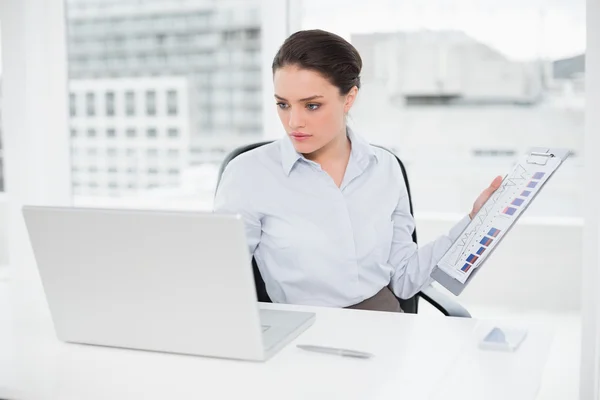 Empresária com gráficos e laptop no escritório — Fotografia de Stock