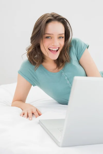 ベッドでノート パソコンで陽気なカジュアルな女性 — ストック写真