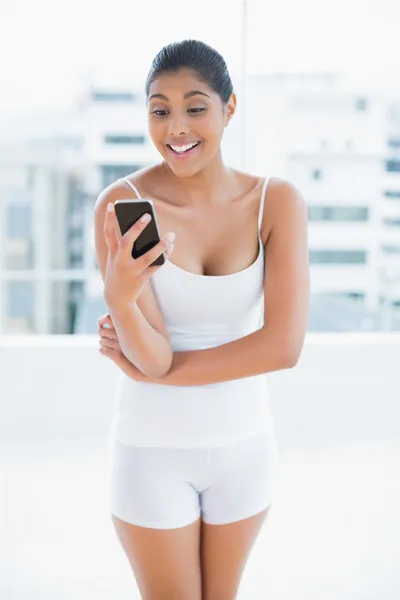 Surprised toned brunette holding smartphone — Stock Photo, Image