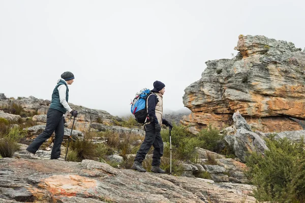 Couple walking through rocky landscape with trekking poles again — Stock Photo, Image