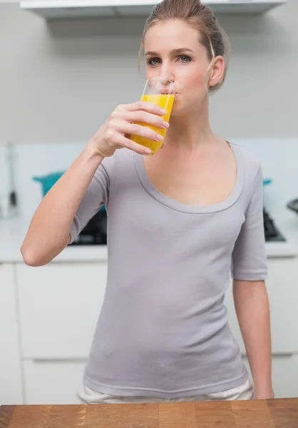 Ruhiges, wunderschönes Model, das in die Kamera schaut und Orangensaft trinkt — Stockfoto