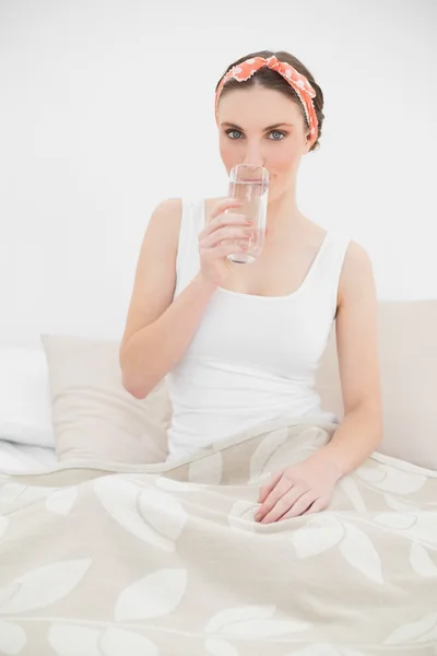 Woman drinking a glass of water looking into the camera — Stock Photo, Image