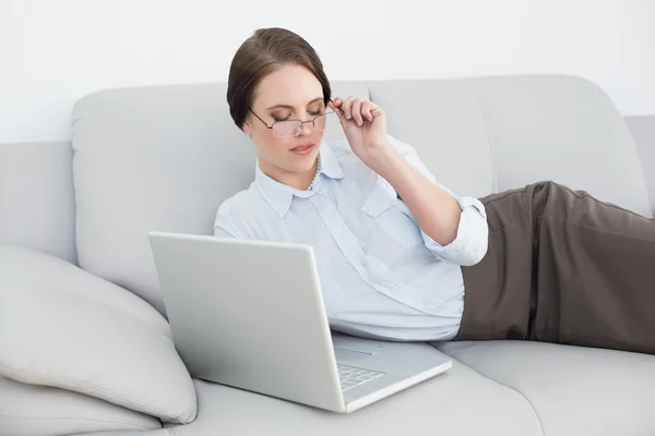 Schick gekleidete Frau mit Laptop auf Sofa — Stockfoto