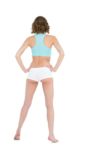 Rear view of slender young woman wearing sportswear posing with hands on hips — Stock Photo, Image