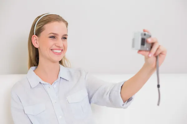 Happy casual blonde sitting on couch taking a picture of herself — Stock Photo, Image