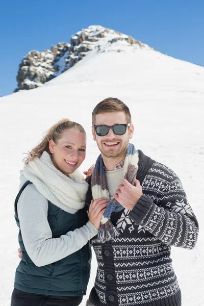 Lächelndes Paar in warmer Kleidung vor verschneitem Hügel — Stockfoto