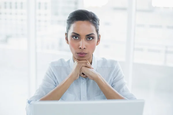 Achtersteven zakenvrouw zit op haar Bureau camera kijken — Stockfoto