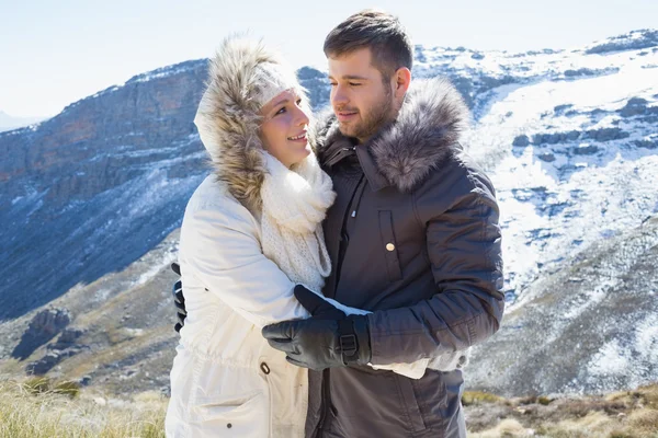 Любящие пары в куртках против снежного горного хребта — стоковое фото