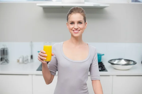 Cheerful gorgeous model looking at camera holding orange juice — Stock Photo, Image