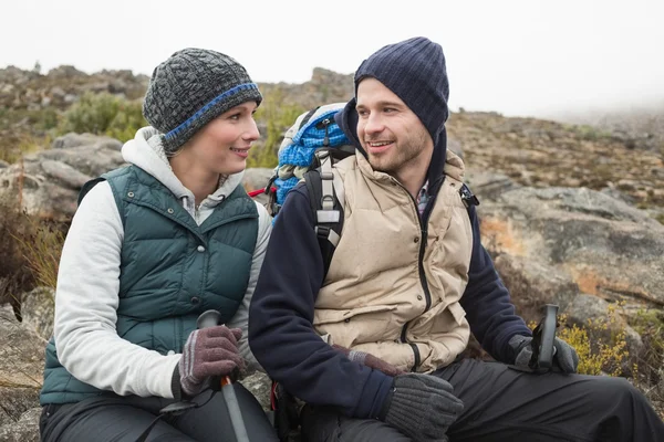 Lächelndes Paar sitzt auf einem Felsen während einer Wanderung — Stockfoto
