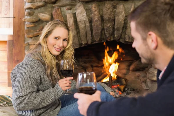 Couple with wineglasses in front of lit fireplace — Stock Photo, Image