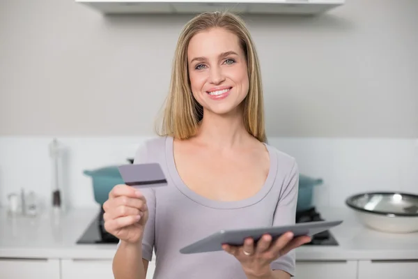 Cheerful gorgeous model holding tablet and credit card — Stock Photo, Image