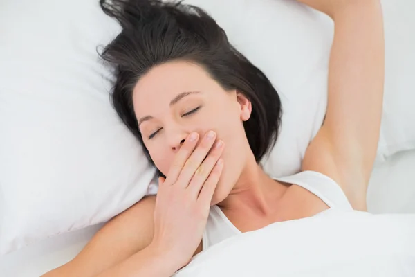 Primer plano de una hermosa mujer bostezando en la cama — Foto de Stock