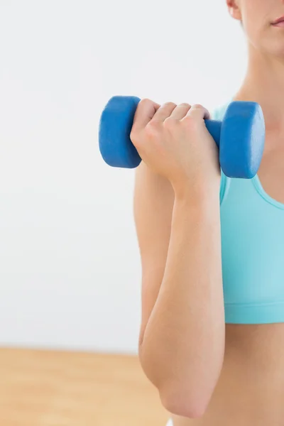 Seção intermediária close-up de uma mulher com halteres no estúdio de fitness — Fotografia de Stock