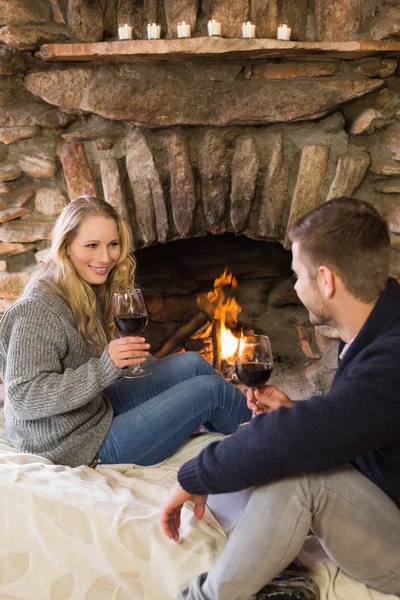 Couple with wineglasses in front of lit fireplace — Stok fotoğraf