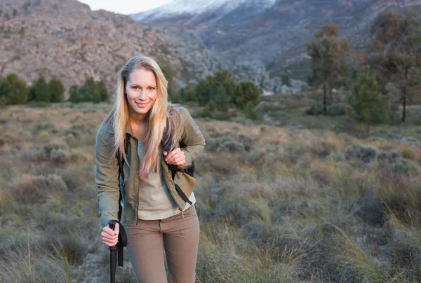 Mujer con mochila y bastones de trekking caminando por el paisaje —  Fotos de Stock