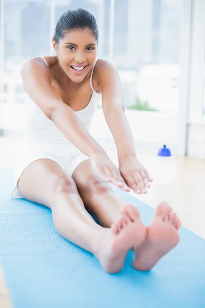 Cheerful toned brunette sitting on floor stretching legs — Stock Photo, Image