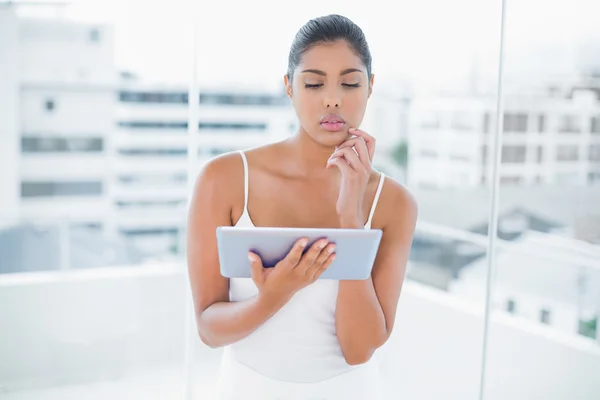 Thoughtful toned brunette using tablet — Stock Photo, Image