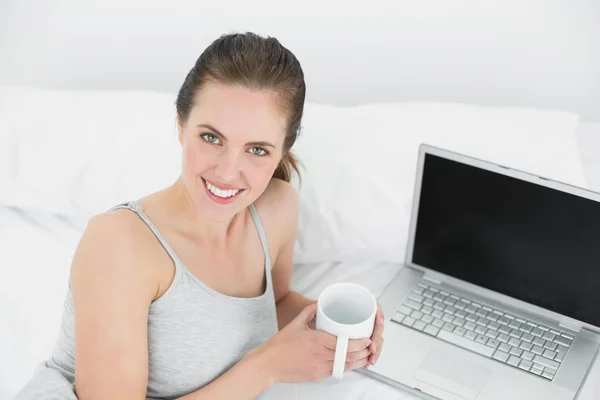 Ritratto di una donna sorridente casual con computer portatile e tazza di caffè in — Foto Stock