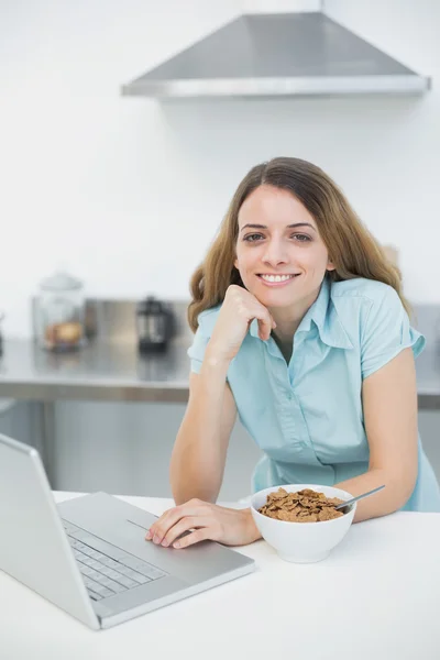 Fröhliche Frau, die mit ihrem Laptop in die Kamera lächelt — Stockfoto