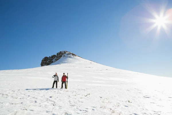 Pareja con tablas de esquí en la nieve en un día soleado —  Fotos de Stock