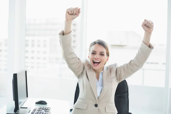 Feliz mujer animadora levantando los brazos sentada en su silla giratoria — Foto de Stock