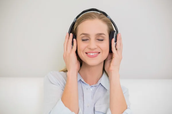 Glimlachend casual blonde luisteren naar muziek met gesloten ogen — Stockfoto