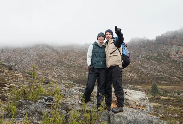 Pareja de pie sobre una roca mirando las montañas — Foto de Stock