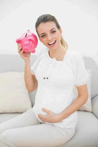 Mulher grávida bonita sacudindo um banco porquinho — Fotografia de Stock