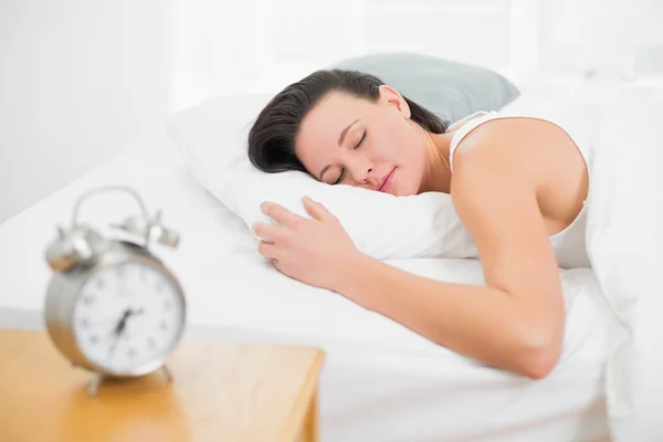Mujer durmiendo en la cama con despertador en la mesita de noche —  Fotos de Stock