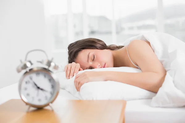 Mujer durmiendo en la cama con despertador en primer plano —  Fotos de Stock