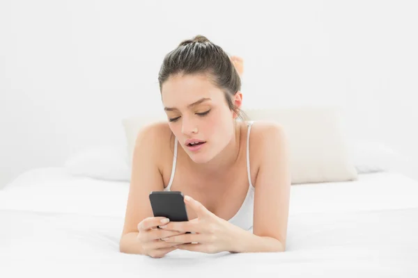 Frau schaut auf Handy im Bett — Stockfoto