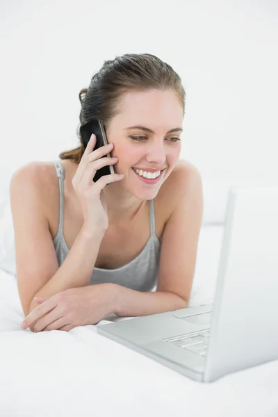 Mujer casual sonriente usando teléfono celular y portátil — Foto de Stock