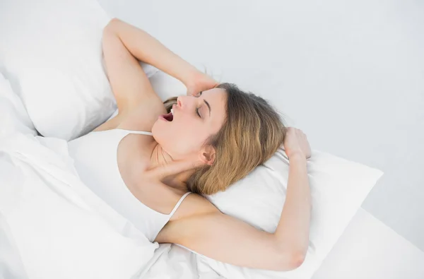 Lovely young woman yawning while lying on her bed — Stock Photo, Image