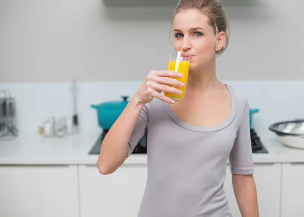 Peaceful gorgeous model looking at camera drinking orange juice — Stock Photo, Image