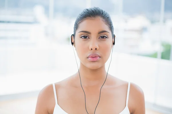 Unsmiling toned brunette listening to music — Stock Photo, Image