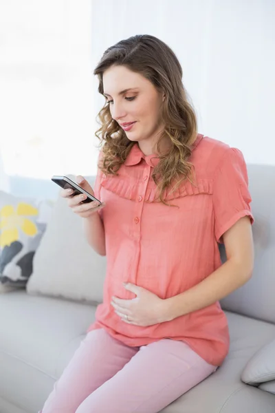 Mulher grávida calma usando seu smartphone — Fotografia de Stock