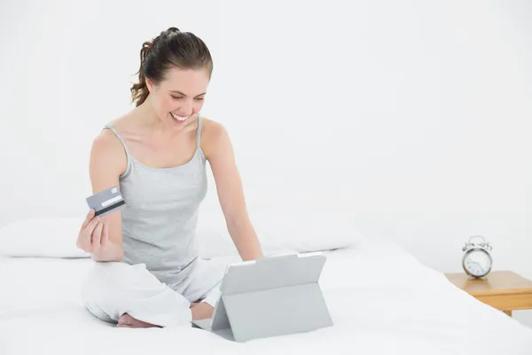 Женщина делает онлайн покупки в постели — стоковое фото