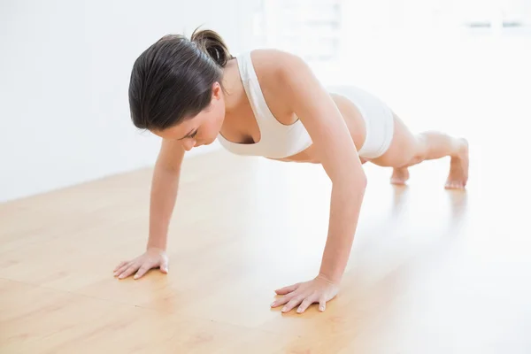 Sportowy kobieta robi push up w fitness studio — Zdjęcie stockowe