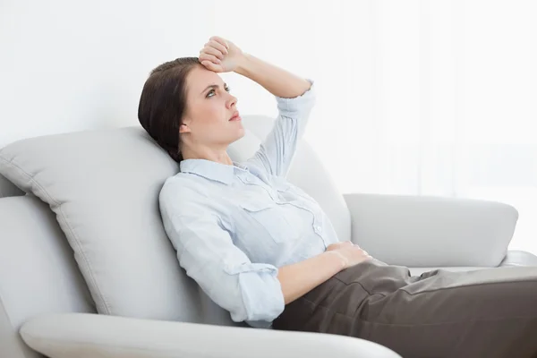 Serious well dressed woman sitting on sofa — Stock Photo, Image