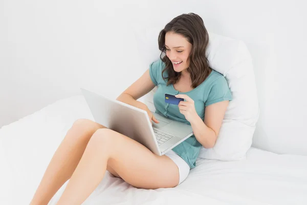 Случайная женщина делает онлайн покупки в постели — стоковое фото