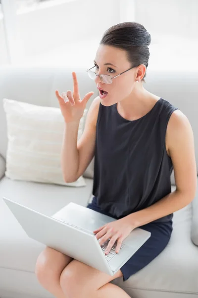 Thoughtful and expressive well dressed woman using laptop — Stock Photo, Image
