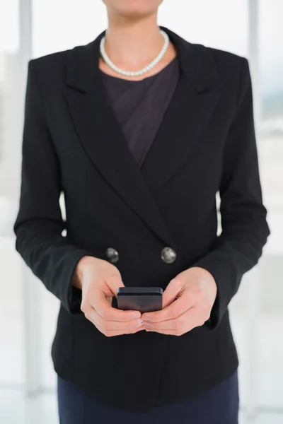 Mid section of businesswoman in suit holding a cellphone — Stock Photo, Image