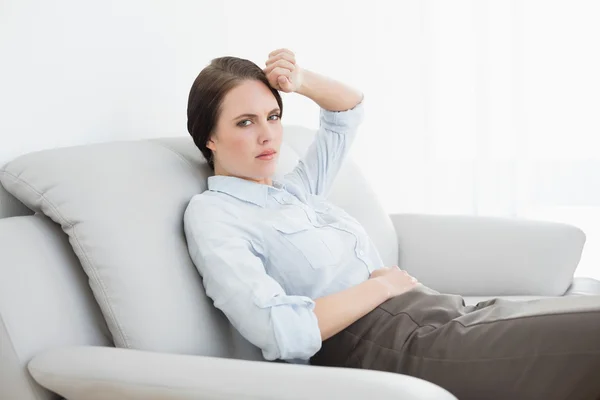 Ernst gut gekleidete Frau sitzt auf Sofa — Stockfoto