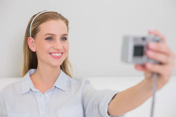 Smiling casual blonde sitting on couch taking a picture of herse — Stock Photo, Image