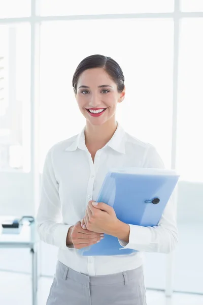 Glimlachende zakenvrouw met map in office — Stockfoto