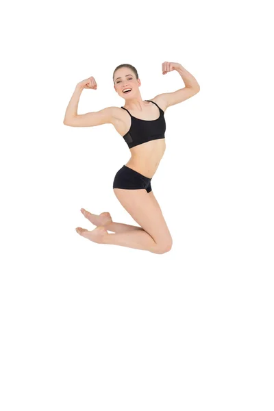 Strong slim model jumping in the air flexing her muscles — Stock Photo, Image